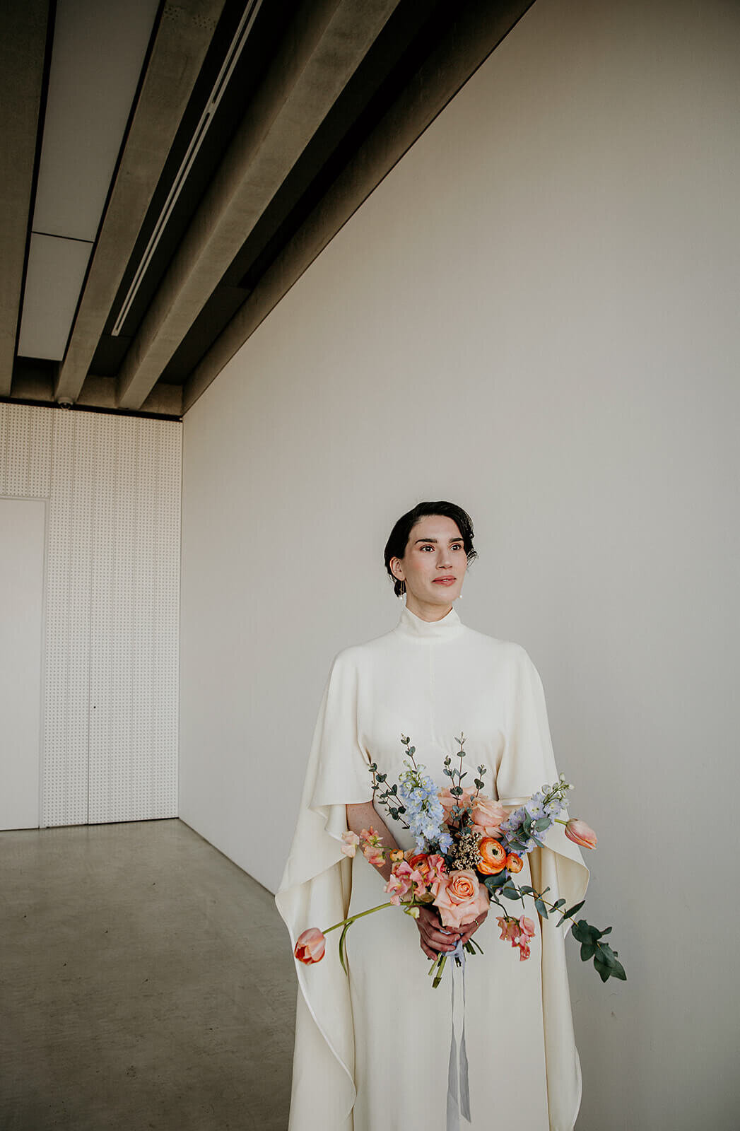 Bride in caped dress standing in The Foyle Room of The Turner Contemporary