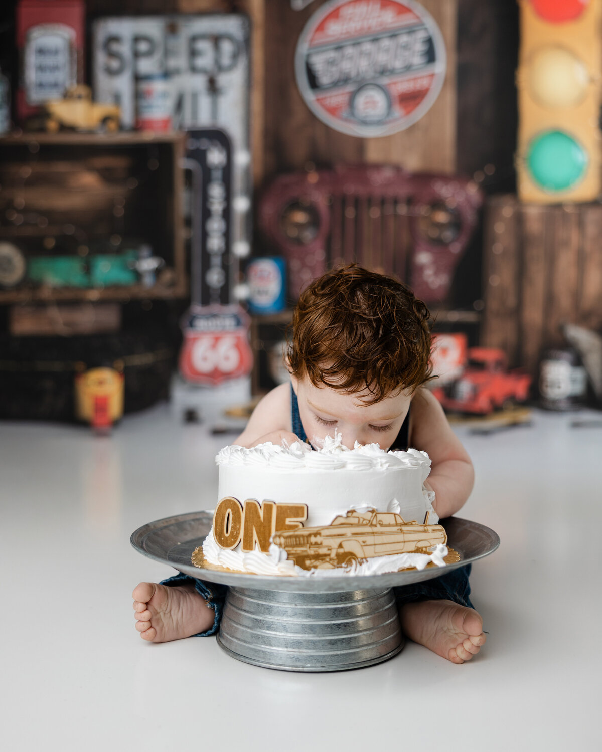 Baby boy leaning forward to take a bite out of his birthday cake during a garage-themed cake smash session.
Photograph by Yucaipa cake smash photographer Kaitlyn Dawn Photography.