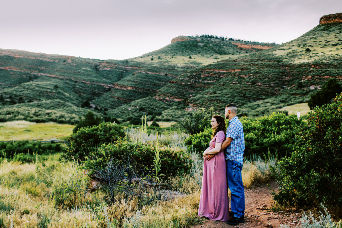 husband wraps arms around wife during maternity session in nature