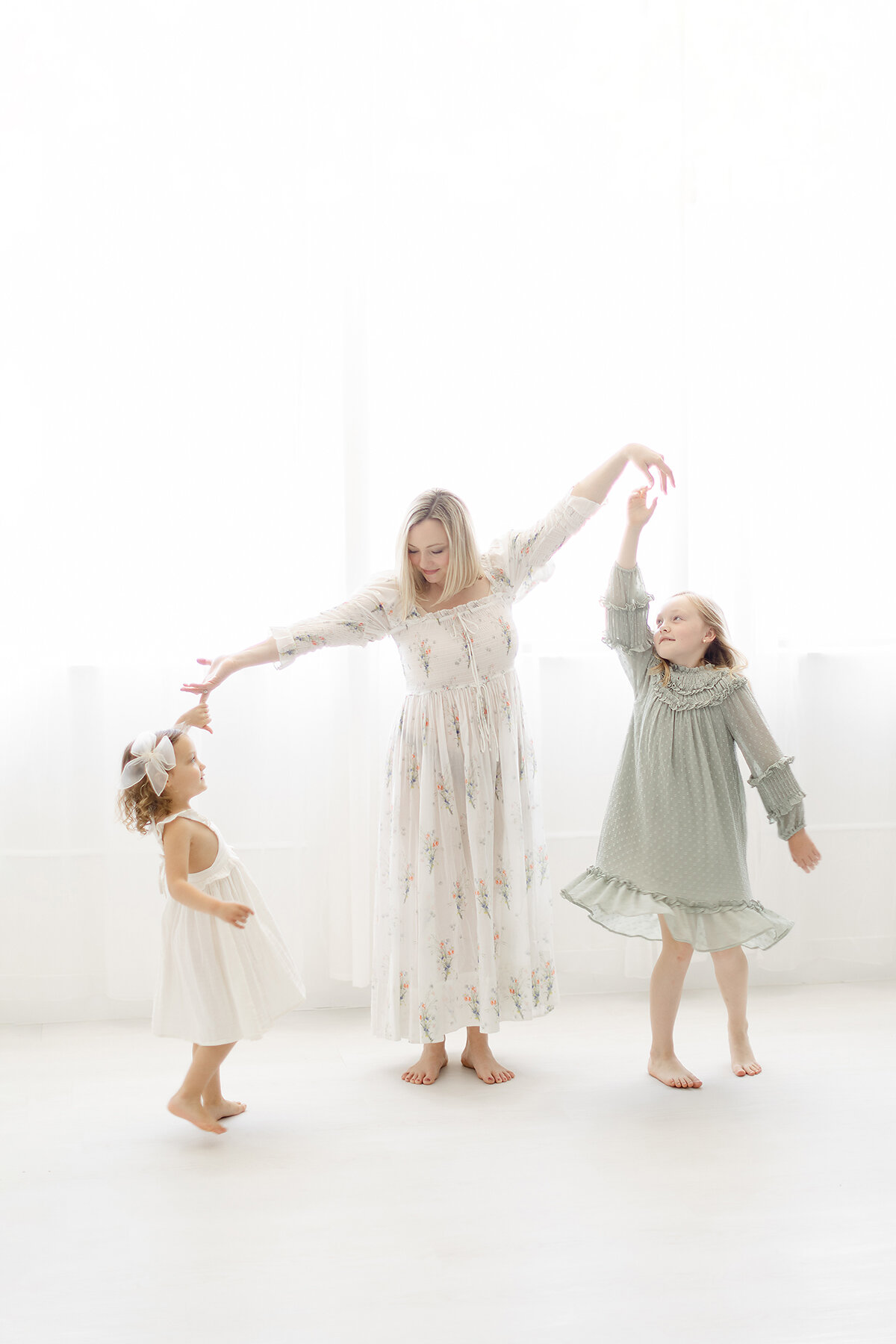 A mother with her two young daughters dancing around a Dallas/Fort worth photography studio.