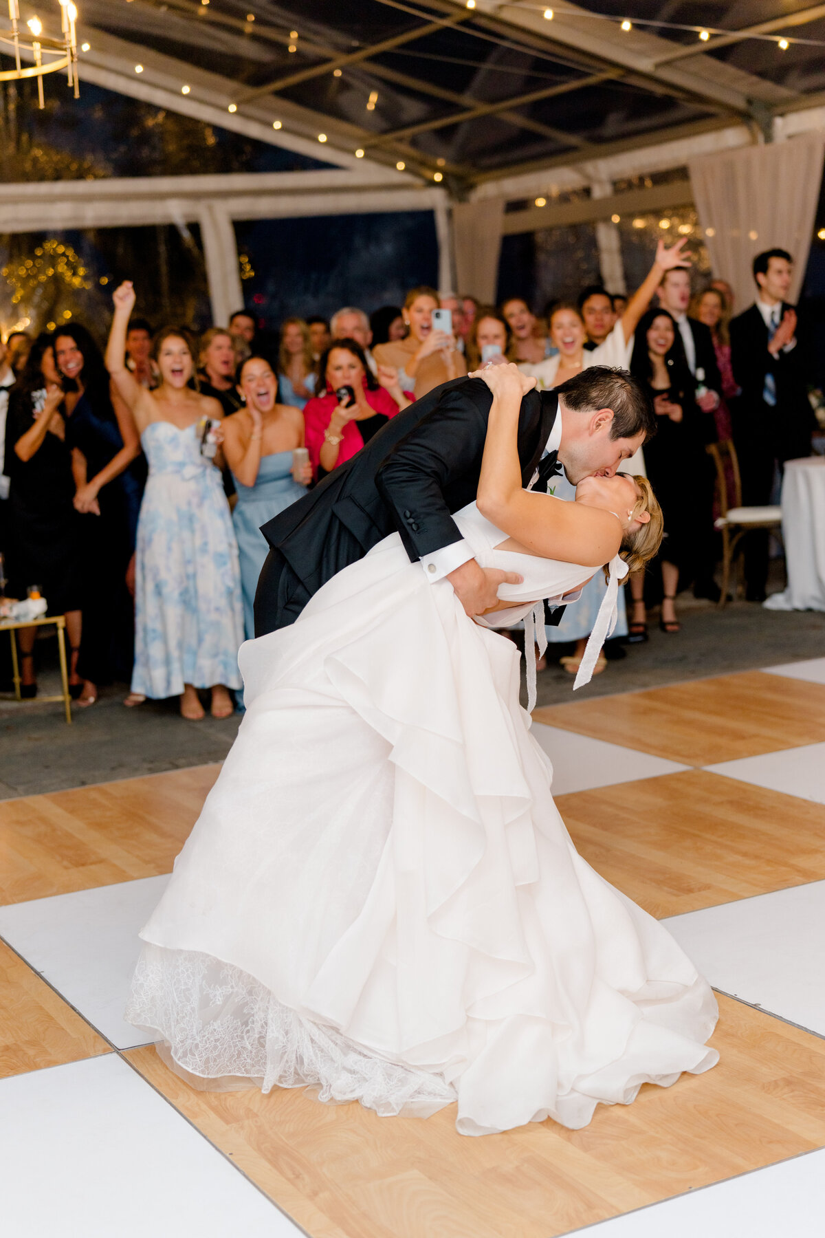 First dance wedding dip kiss with the crowd celebrating in the background. Lowndes Grove spring wedding in Charleston. Kailee DiMeglio Photography.
