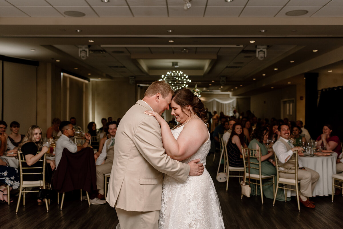 bride and groom have a first dance while guests look on