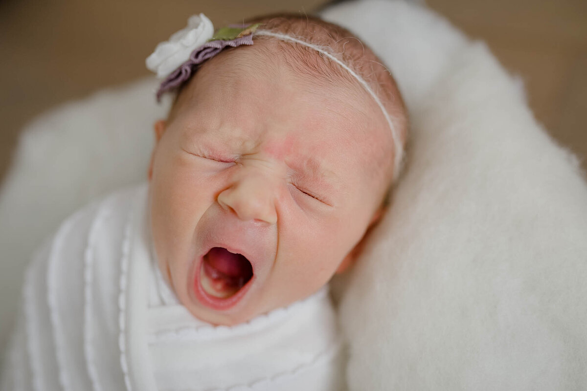 baby yawning wearing a white swaddle