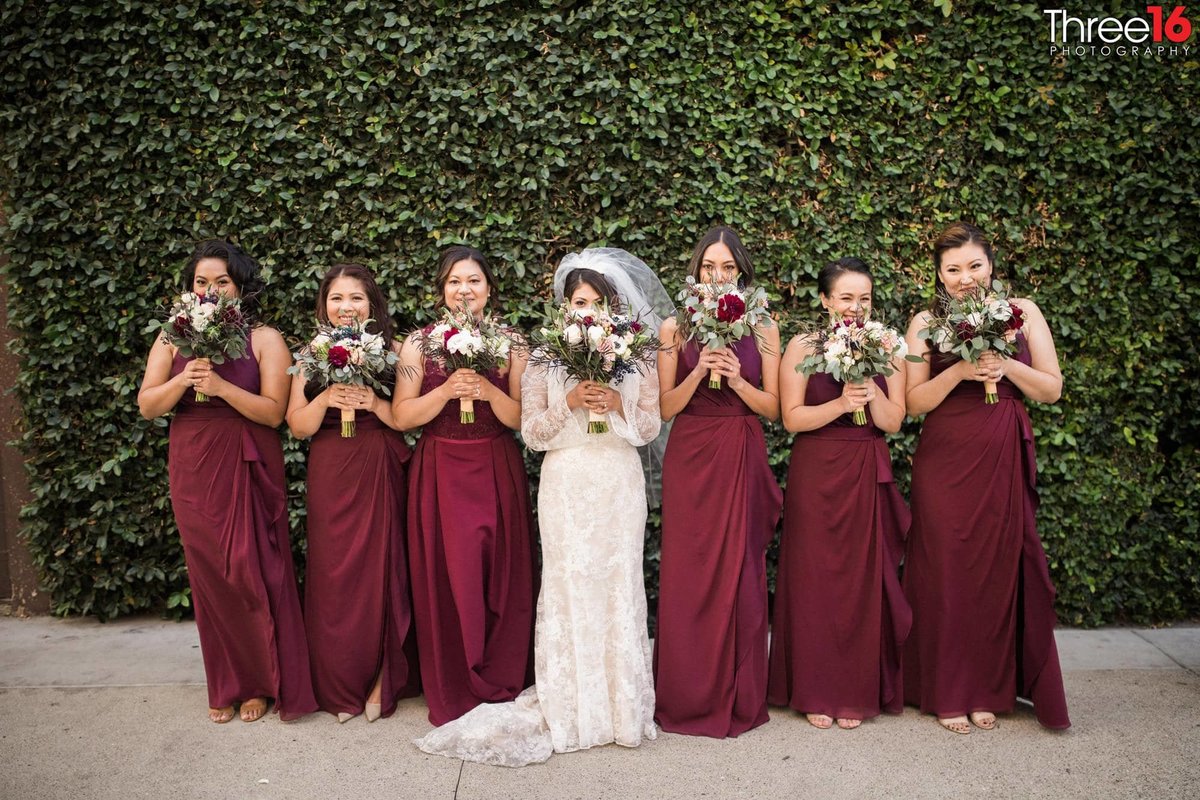 Bride poses with her Bridesmaids as they smell their flowers