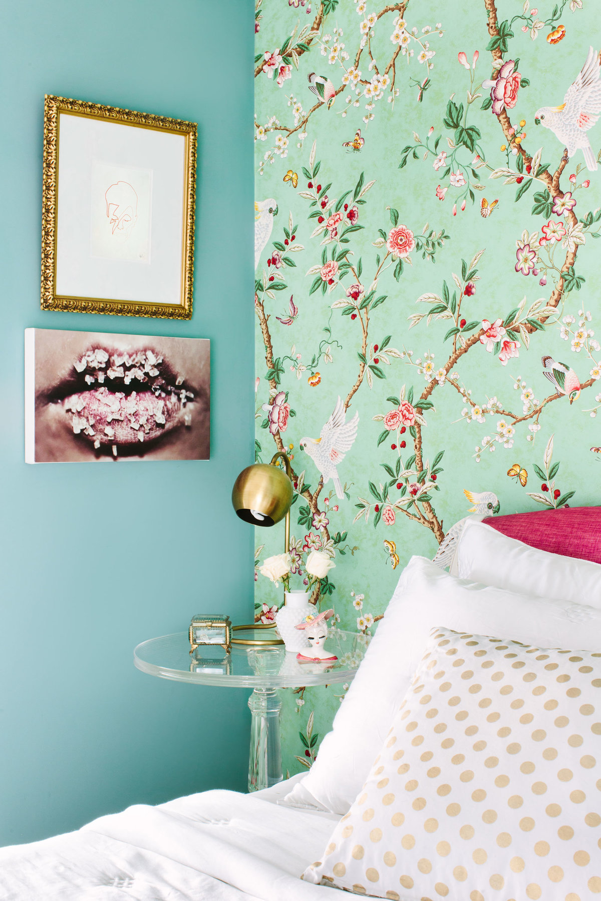 Bedroom with floral wallpaper, pink headboard, and Lucite acrylic nightstand