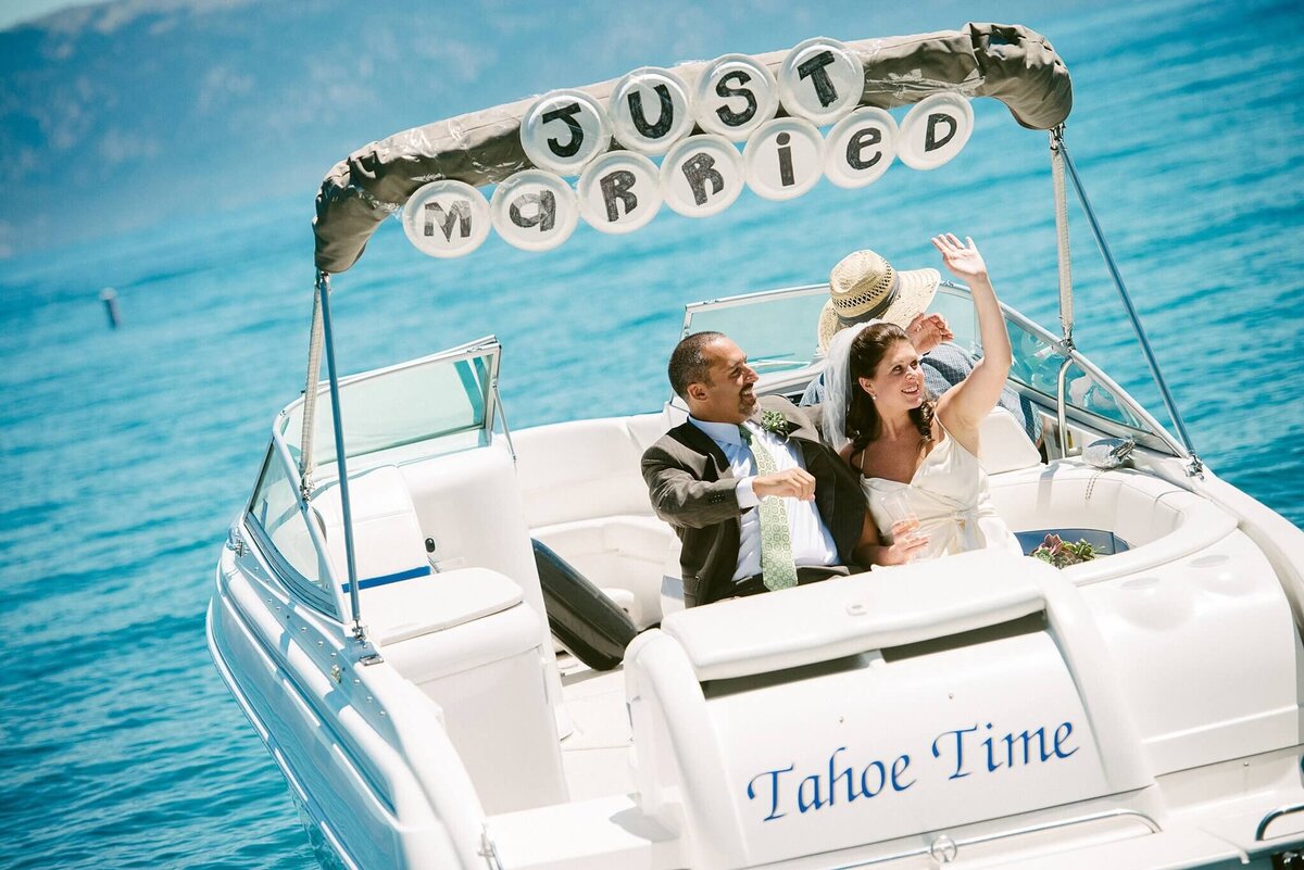 bride and groom in back of speedboat with just married sign