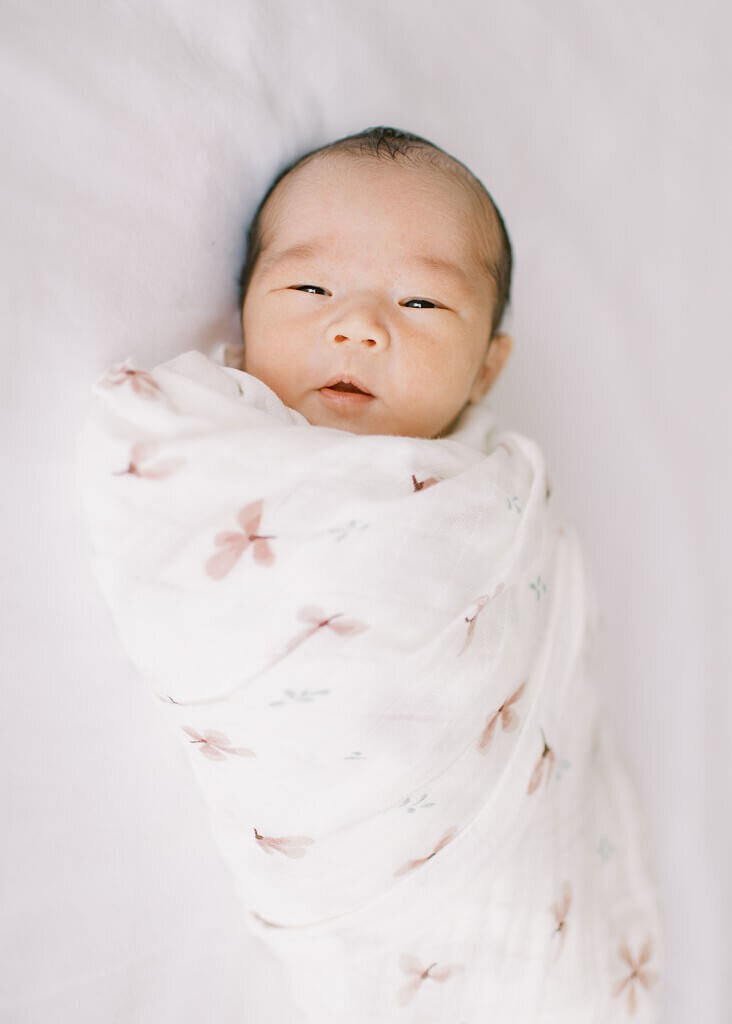 Tiny swaddled newborn with eyes open.