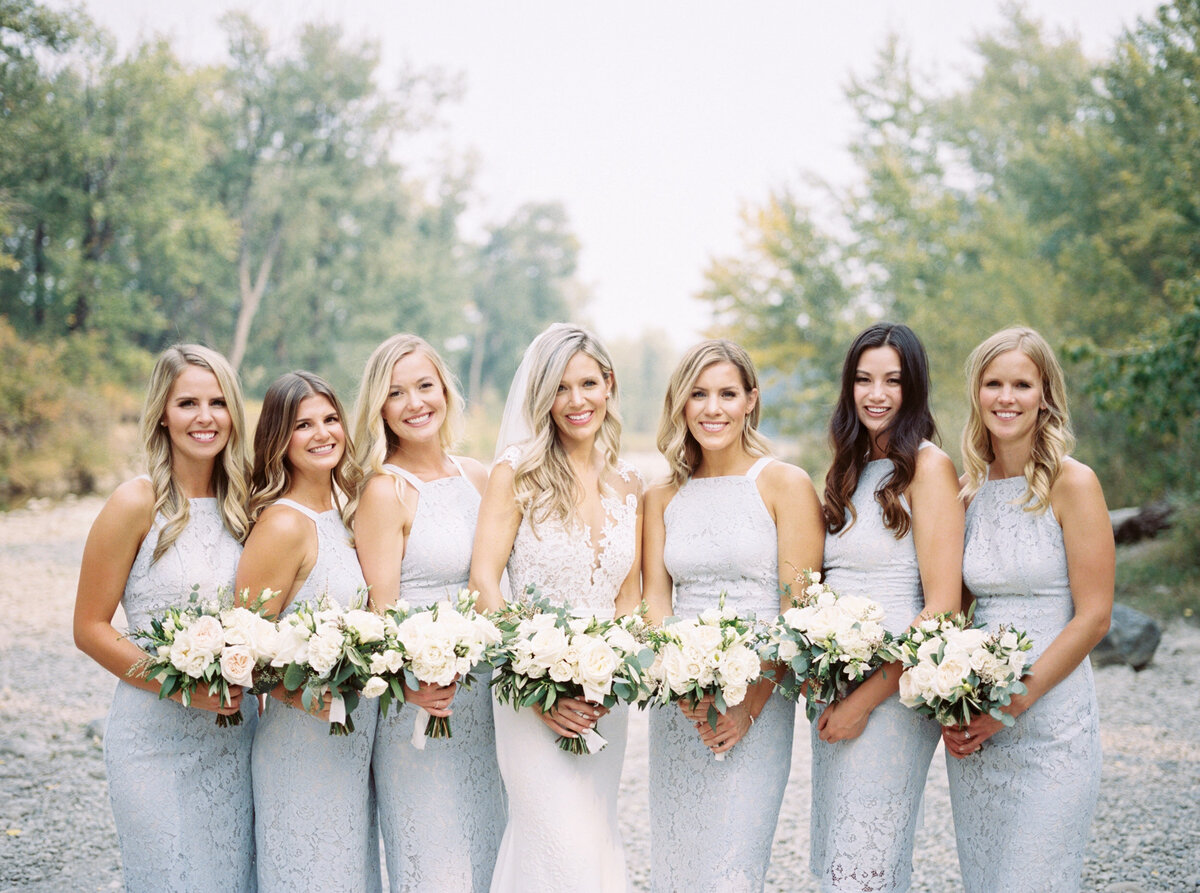 a group of brides maids with flower bouquets  posing for a photo during their Calgary wedding day