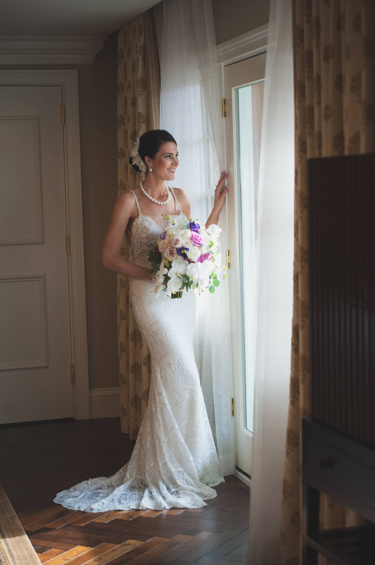 Bride happily gazing out the door of her bridal suite and eager to see her groom