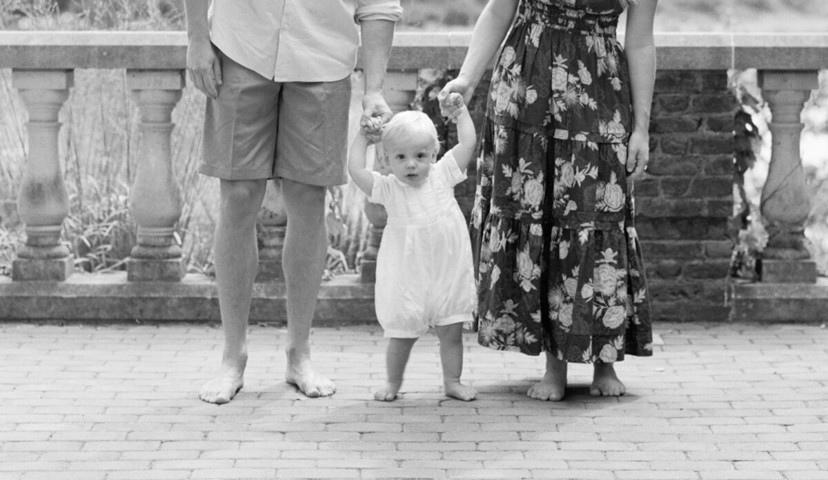 young boy standing between his parents holding their hands
