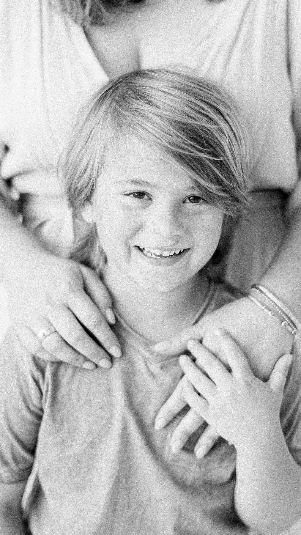 Close up black and white portrait of a young boy looking at the camera smiling for his in studio family session.