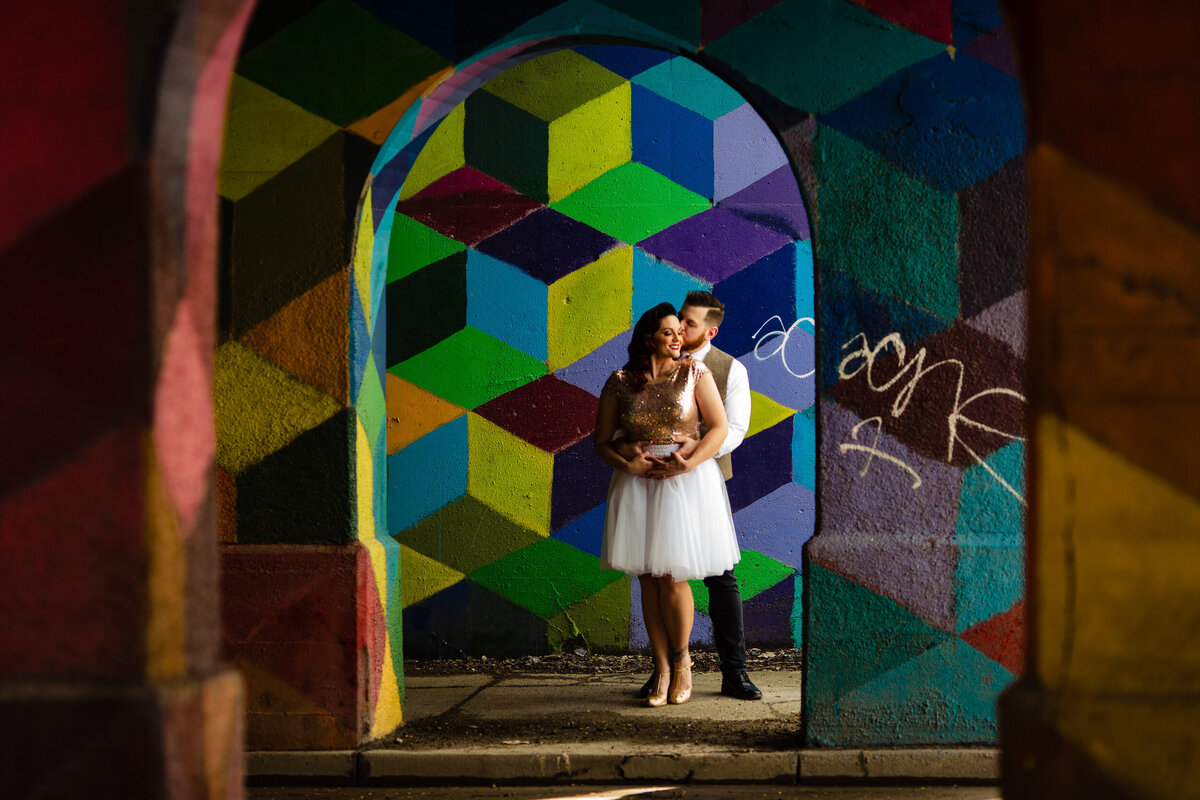 Classy Downtown Detroit Engagement photo of couple standing in front of a colorful wall laughing with each other. Photo By Adore Wedding Photography. Toledo Wedding Photographers