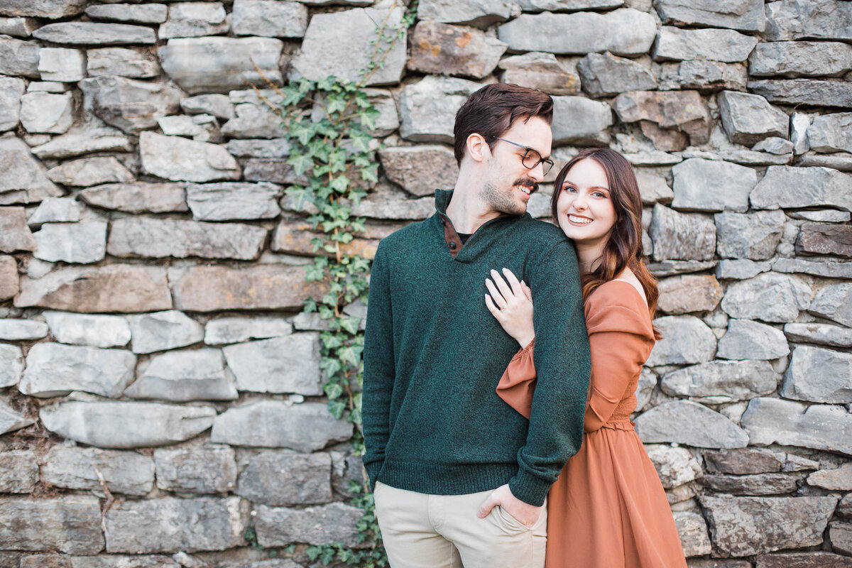 engaged couple posing next to a wall at session in fall
