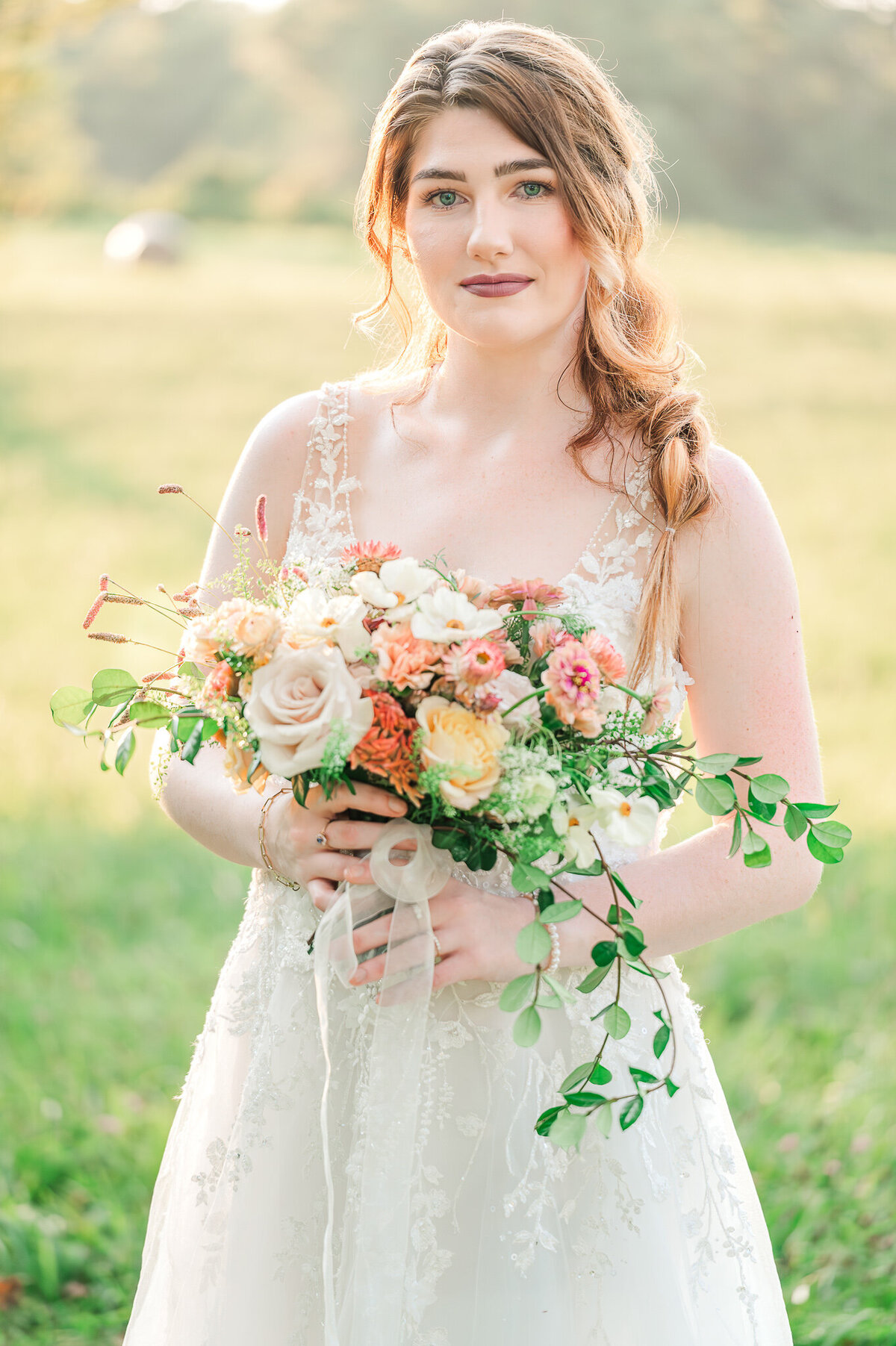 A bride in the North Carolina countryside in the summer holding her wedding bouquet enjoying her North Carolina wedding photos