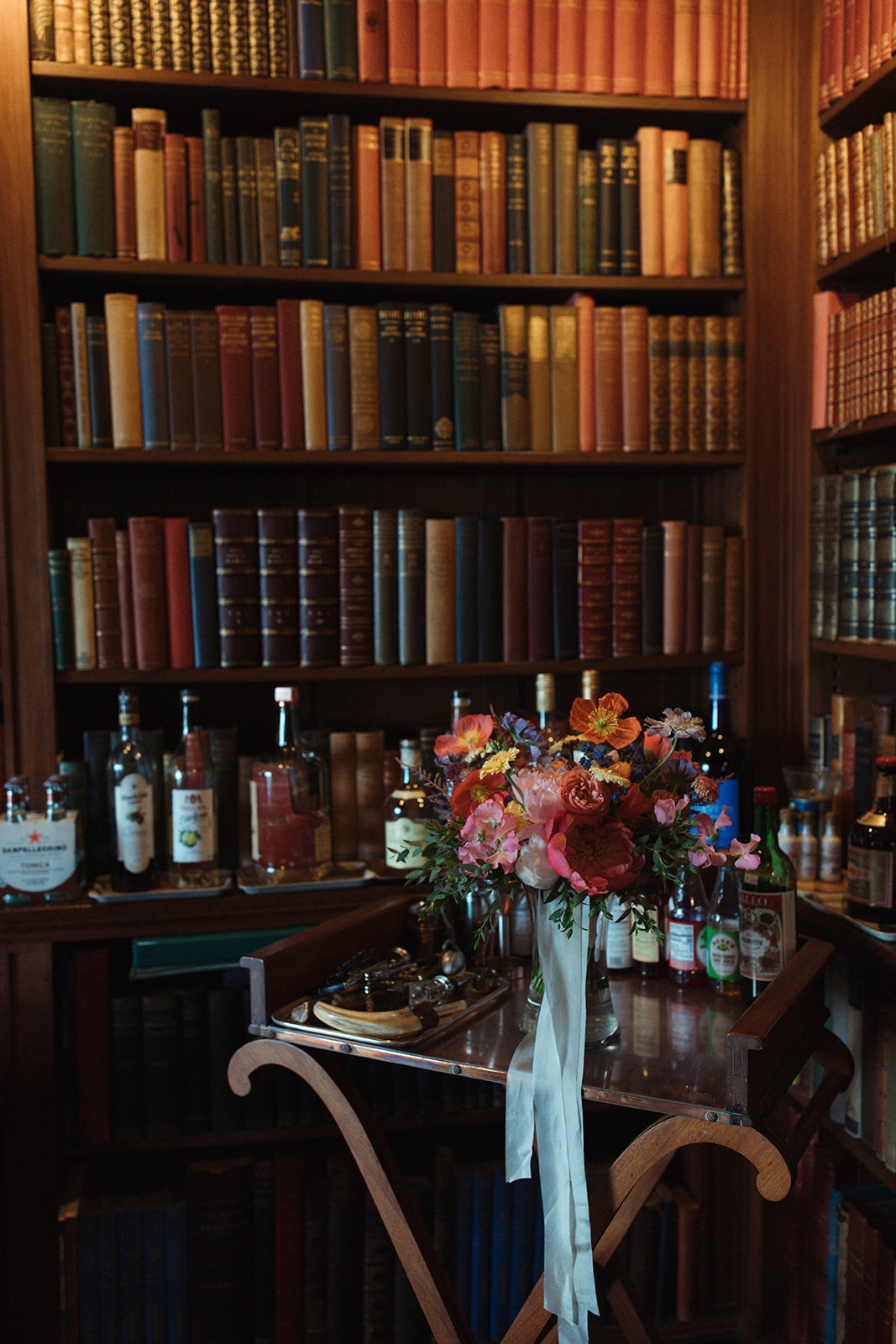 a colorful bouquet of flowers on a bar cart in the library of a castle in the adirondacks