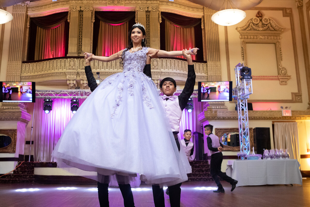 Mexican-American teenage girl in purple ballgown lifted by her court choreographed dance New York Westchester quinceanera Photographer Milestone images