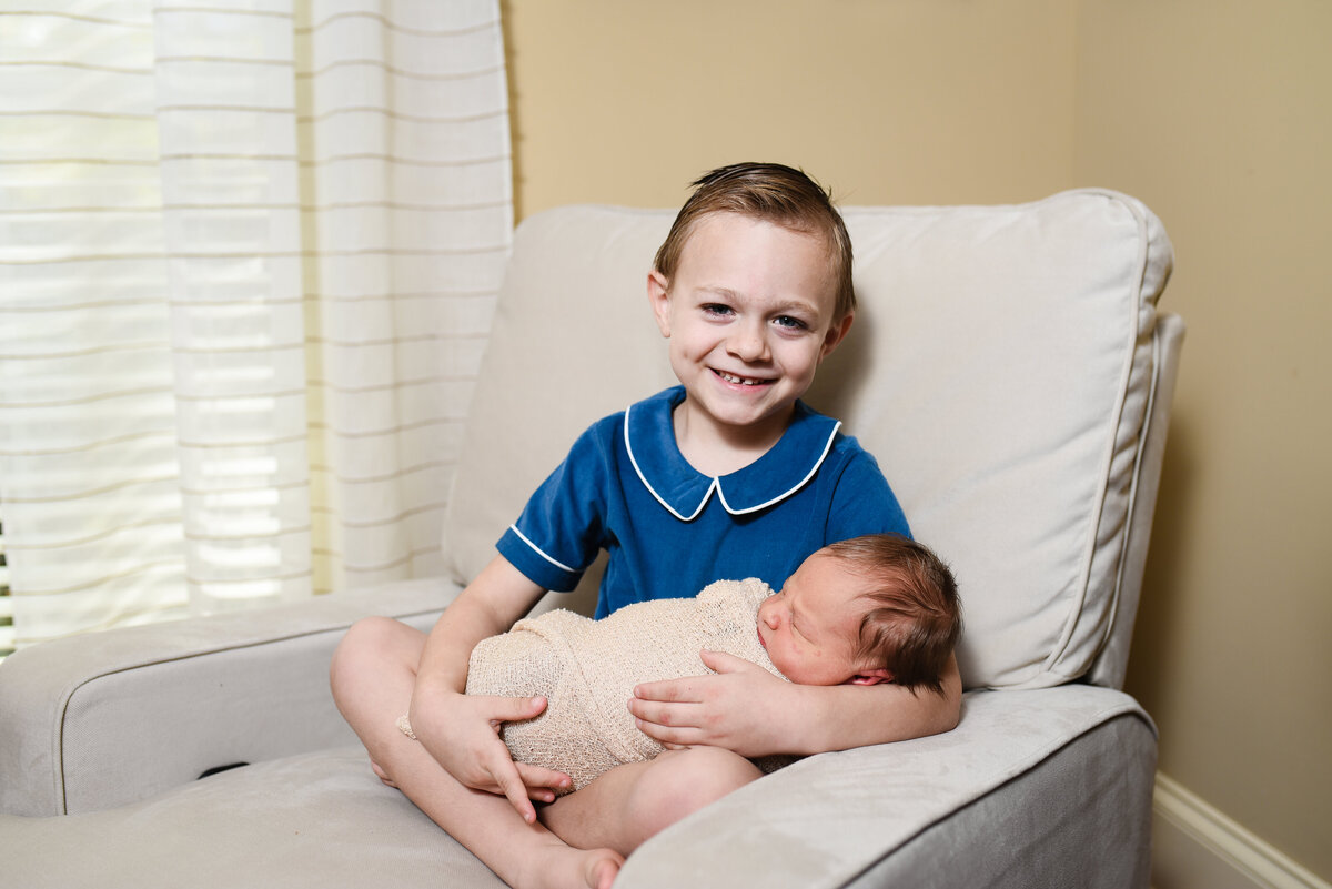 Beautiful lifestyle newborn photography: Big brother holds newborn brother at home in his nursery in Madison, Mississippi