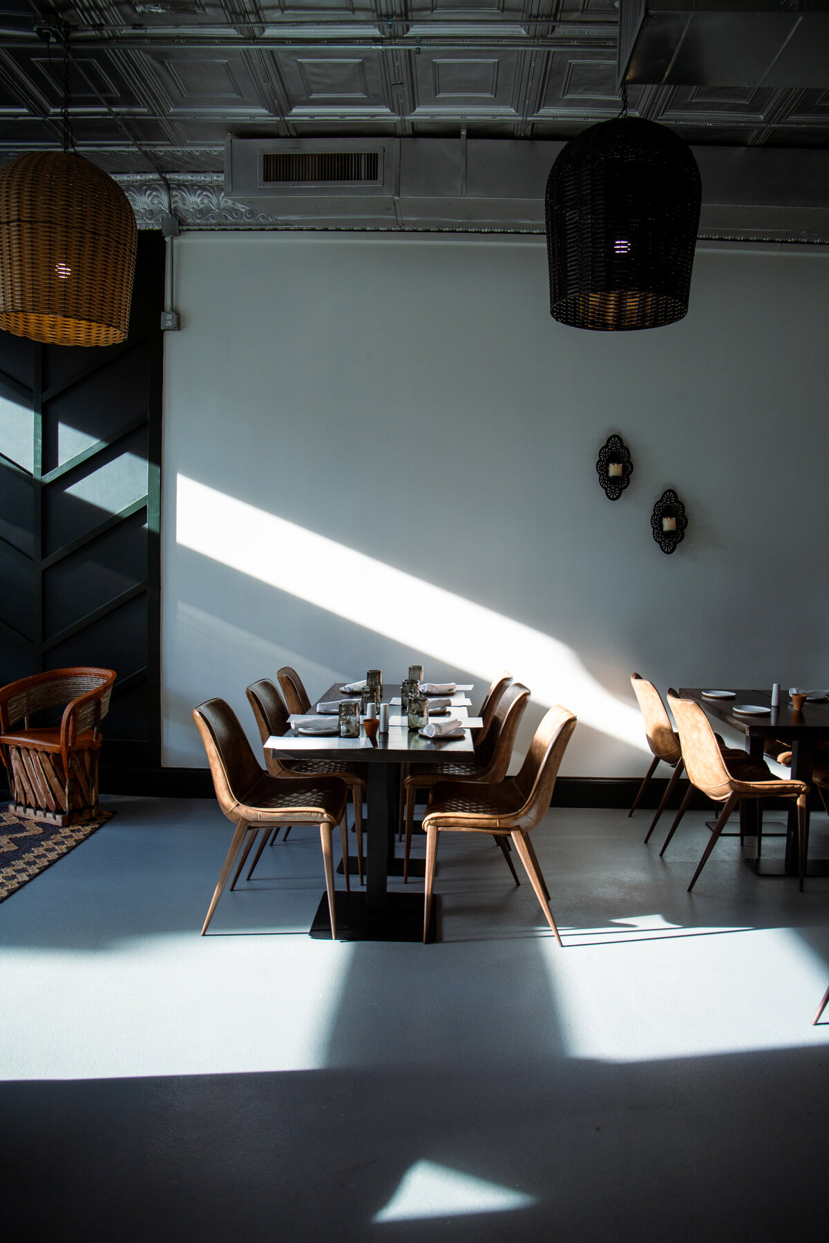 A table and chairs on the interior of a restaurant with a sun beam cutting through the image.