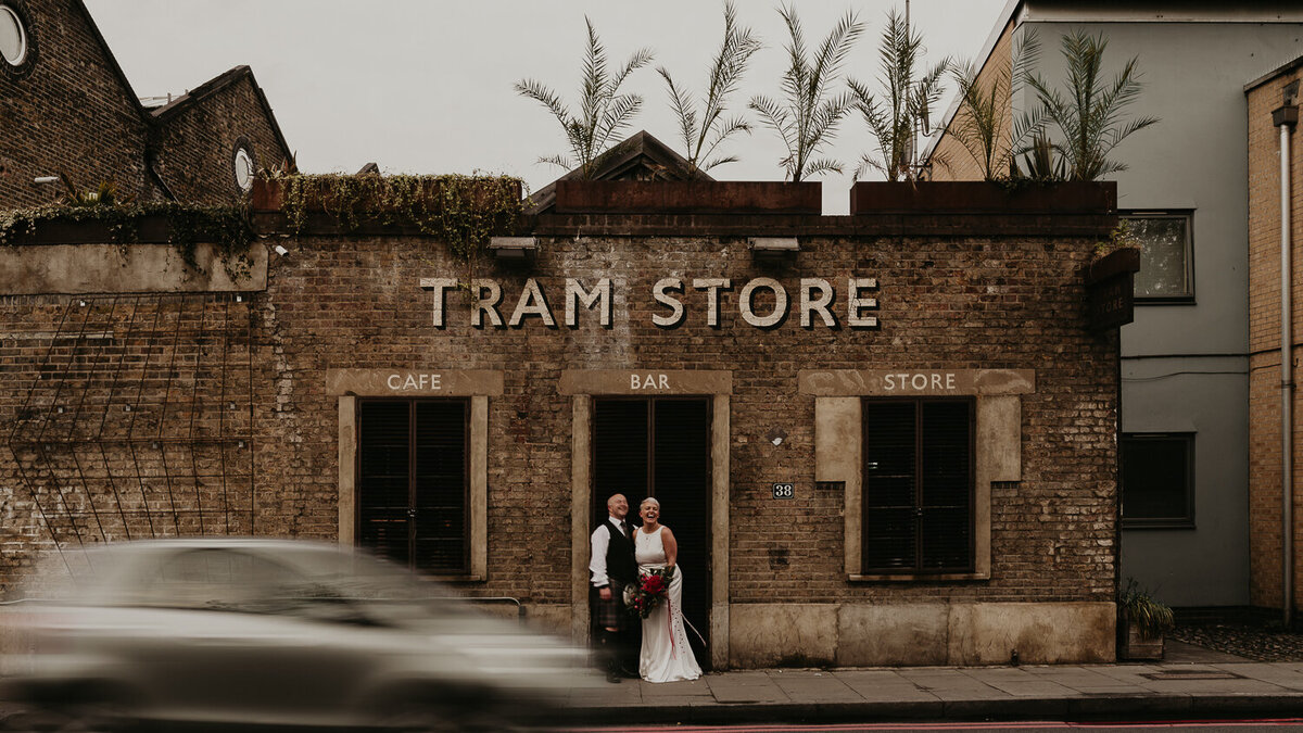 A bride and groom stand outside Tram Store, a wedding venue in Clapton London that has an industrial feel.