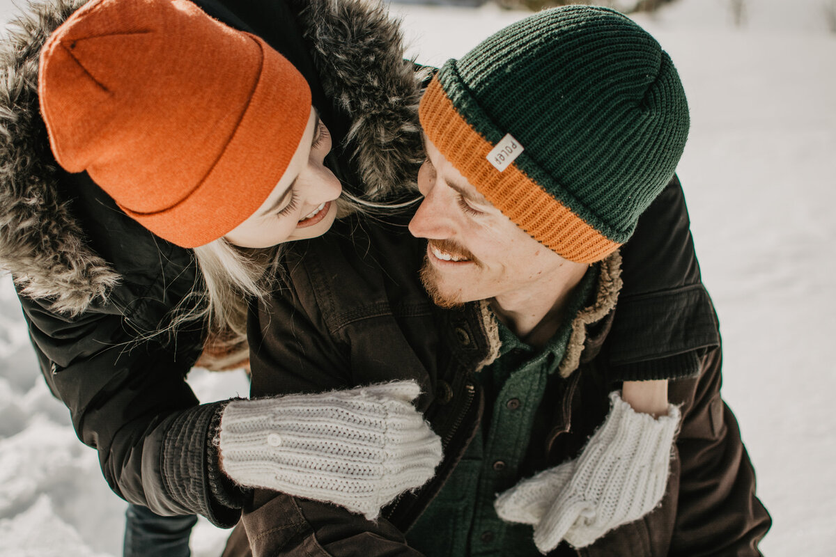 jackson hole photographers captures man looking and smiling at his fiance as she leans over his shoulder to look at him while they are in Jackson Hole for their engagement session