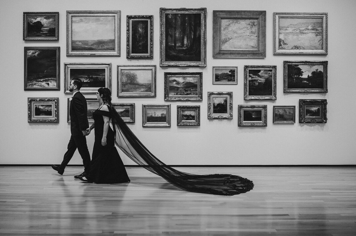 Non tradtional couple walk past framed art wall in Akron