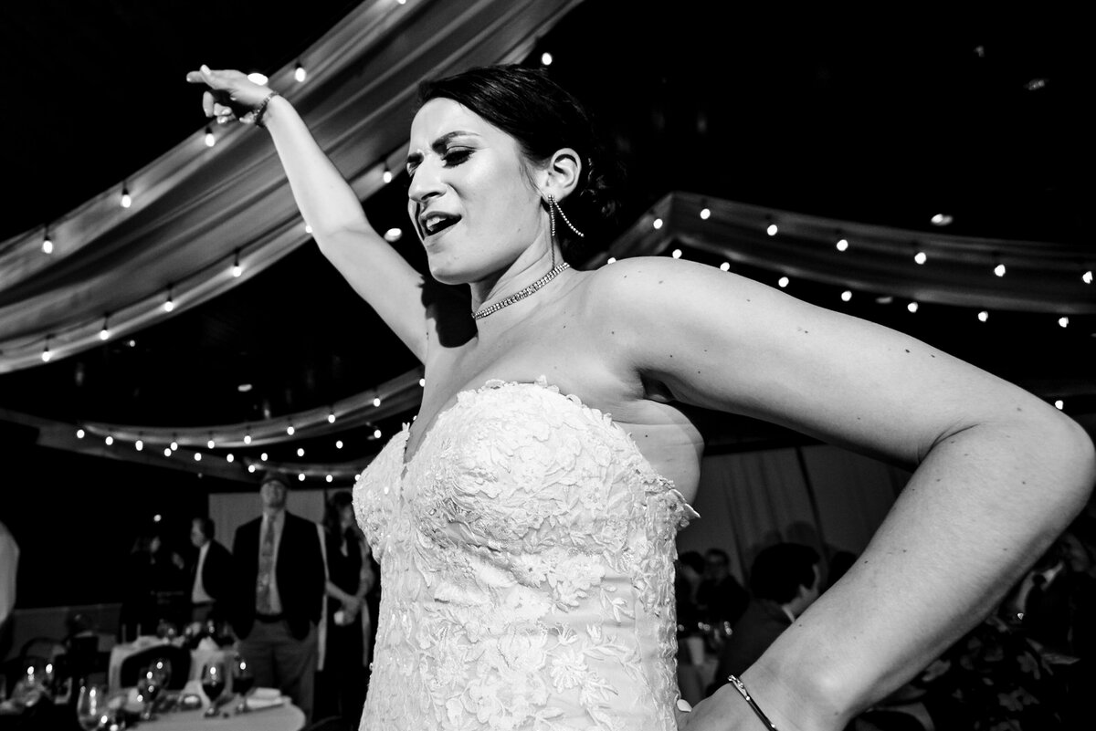 Black-and-white-up-close-low-angle-photograph-of-a-bride-busting-a-dance-move-during-her-wedding-reception-at-Childress-Vineyards