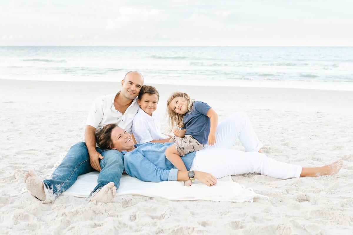 Family laying on a blanket at the beach