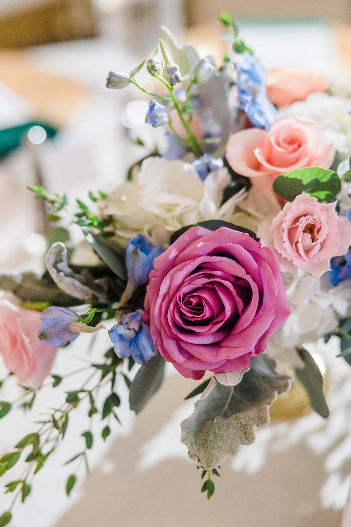 Close-up image of a vibrant floral arrangement for events in Davenport, featuring a prominent pink rose, surrounded by light pink roses and blue flowers.