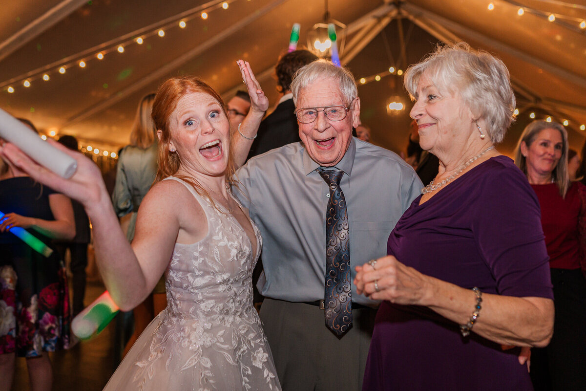 A bride dancing with her grandparents during her wedding reception at Agapae Oaks by JoLynn Photography, a Raleigh wedding photographer