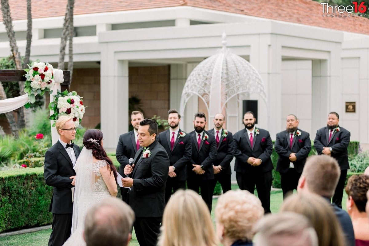 Groom reads his vows to his Bride as the Groomsmen watch