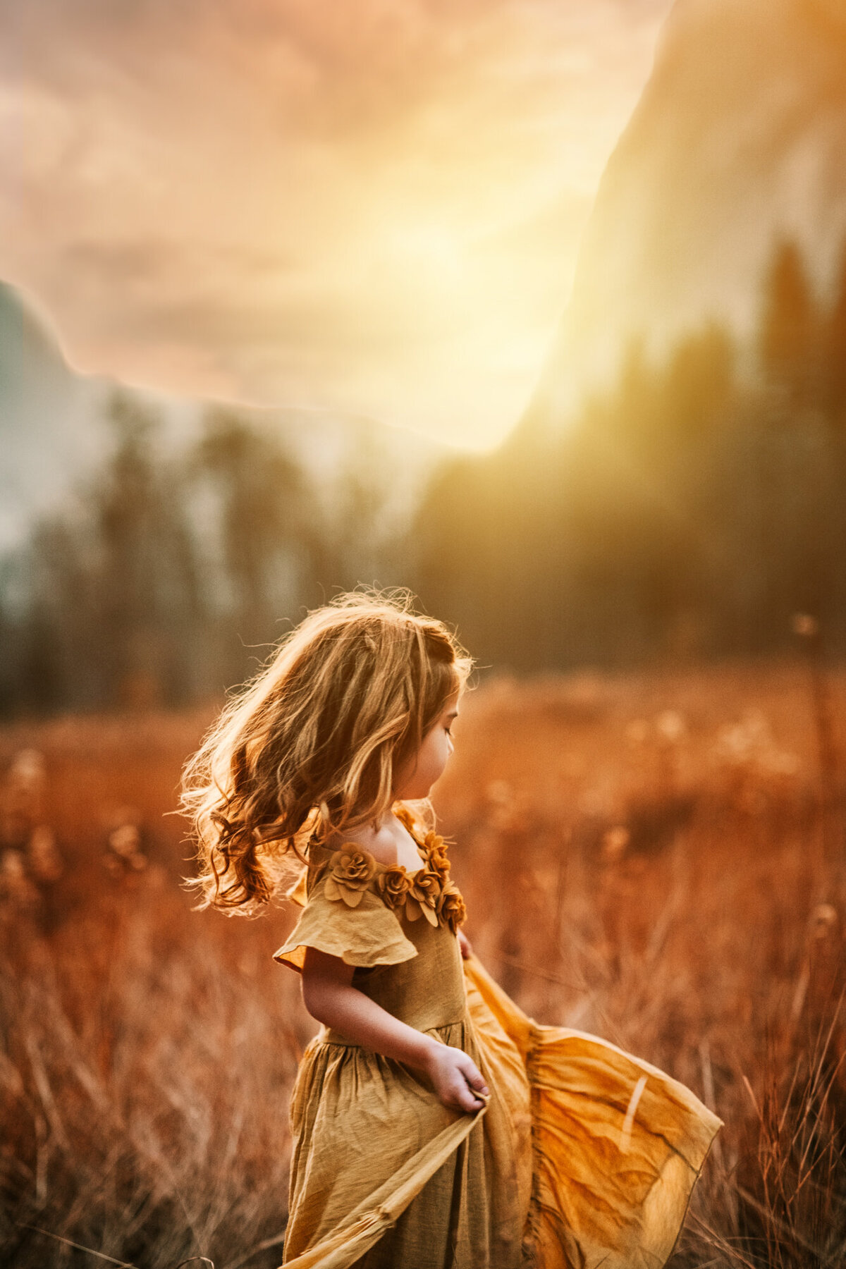 Little girl in a gold dress is twirling at Yosemite.