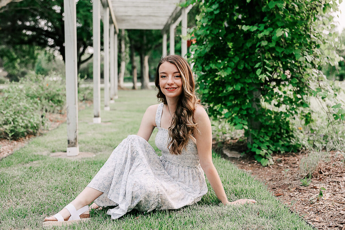 Senior sitting on grass with white dress on