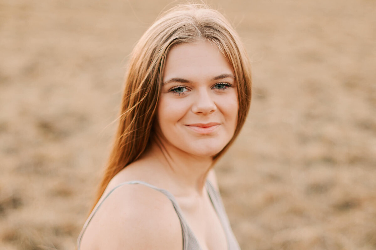 A teenage girl in a gray tank top looks at the camera smiling Salem Oregon Senior Photography