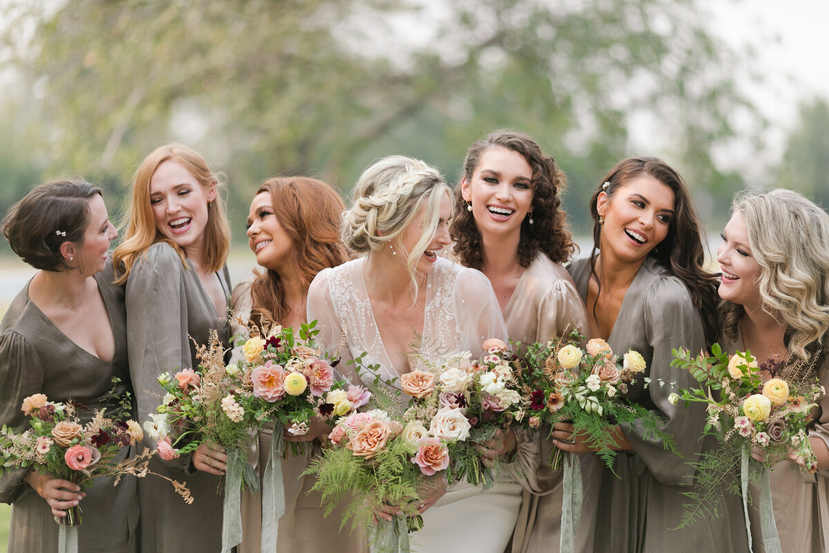 bride and bridesmaids laughing holding flowers