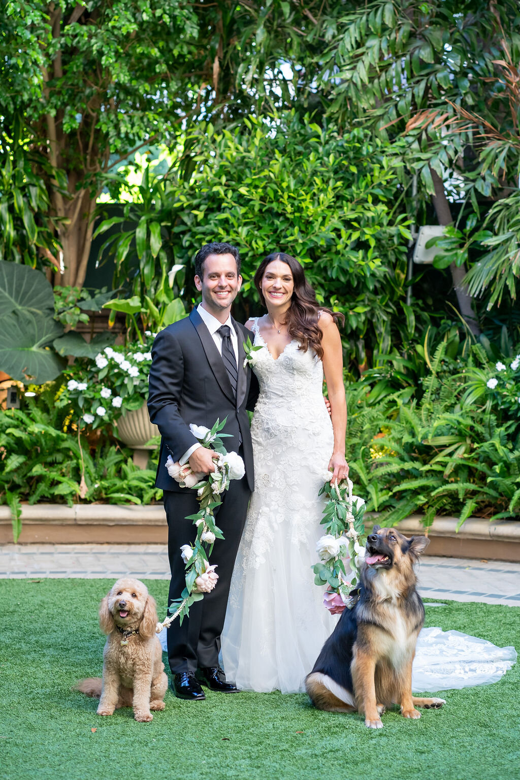 bride, groom and their 2 dogs with floral leashes