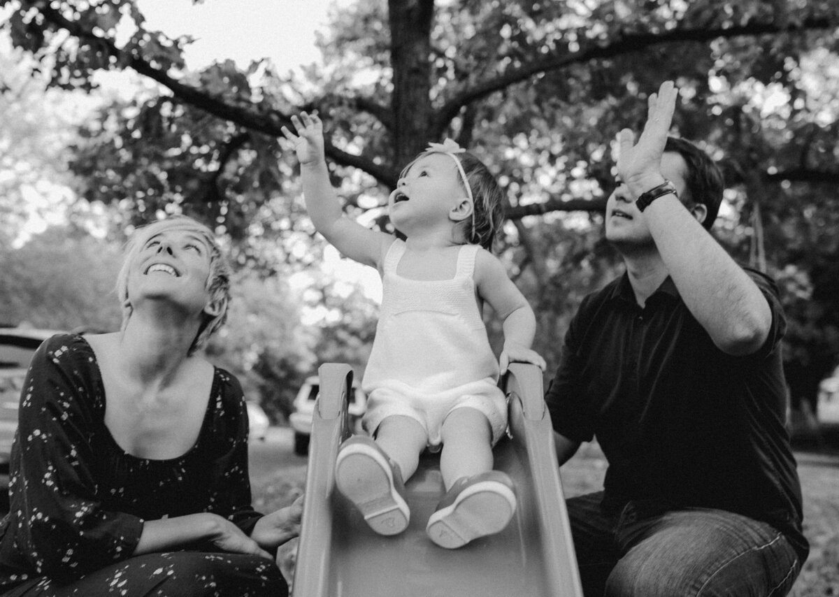 Child on slide with mother and father looking up at Austin family photo session
