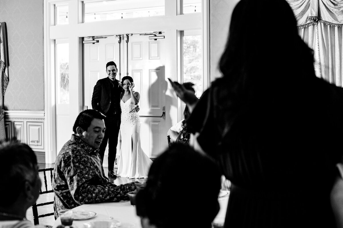 black and white photo of bride getting teary eye during her sisters toast at their micro wedding