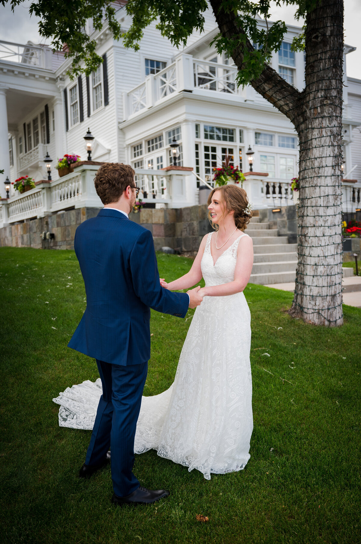 A bride and groom hold hands during their first look at The Manor House, captured by Denver wedding photographer Two One Photography.