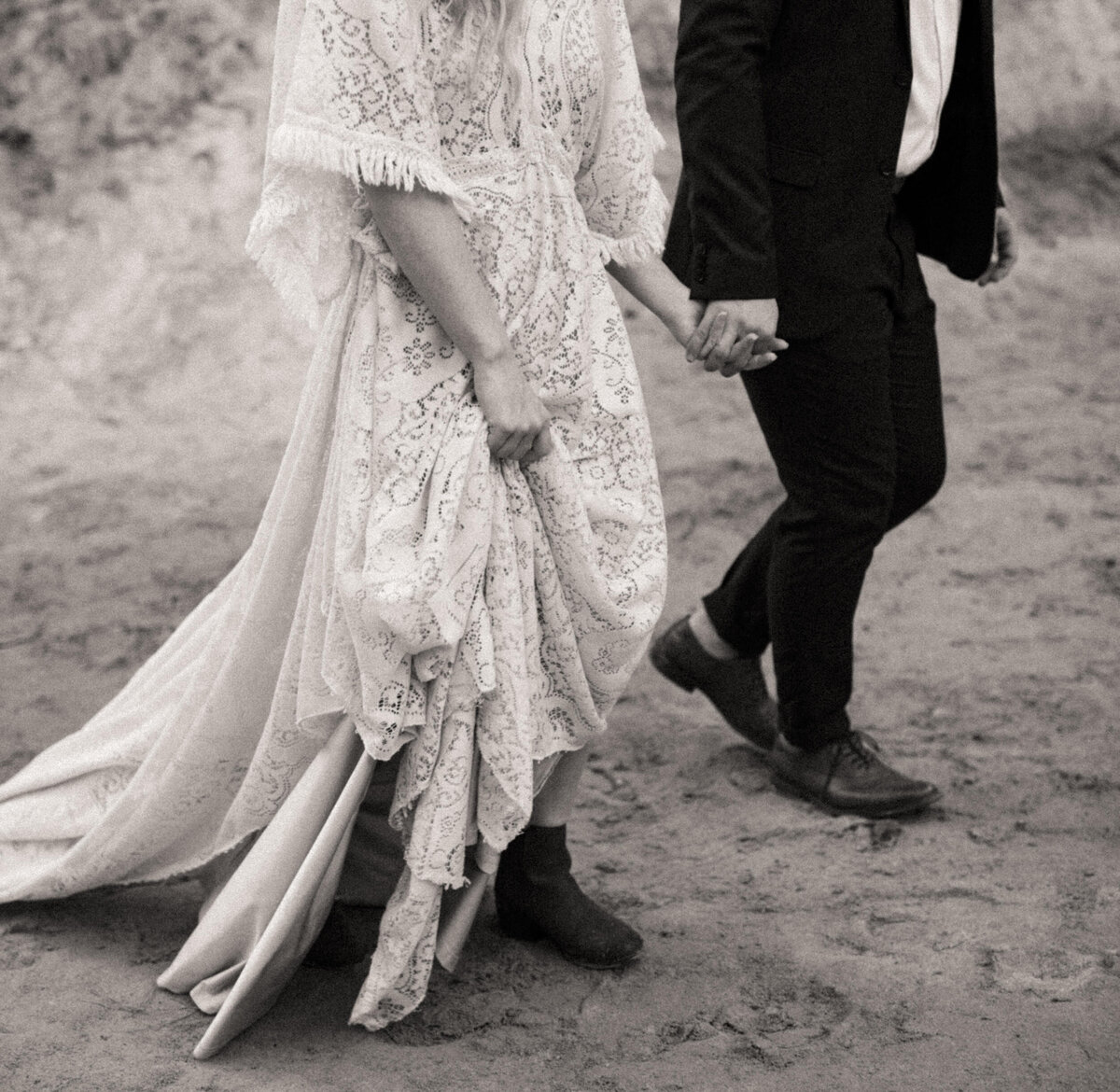 Bride holding up het vintage wedding dress as she walks holding hands with her groom