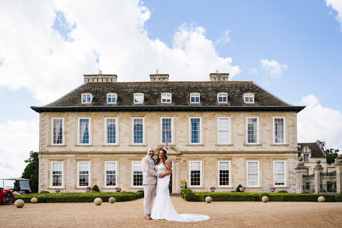 Wedding couple posign for a photo in front of Stapleford Park Hotel