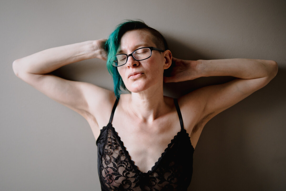 A person in lingerie with their arms stretched behind their head.