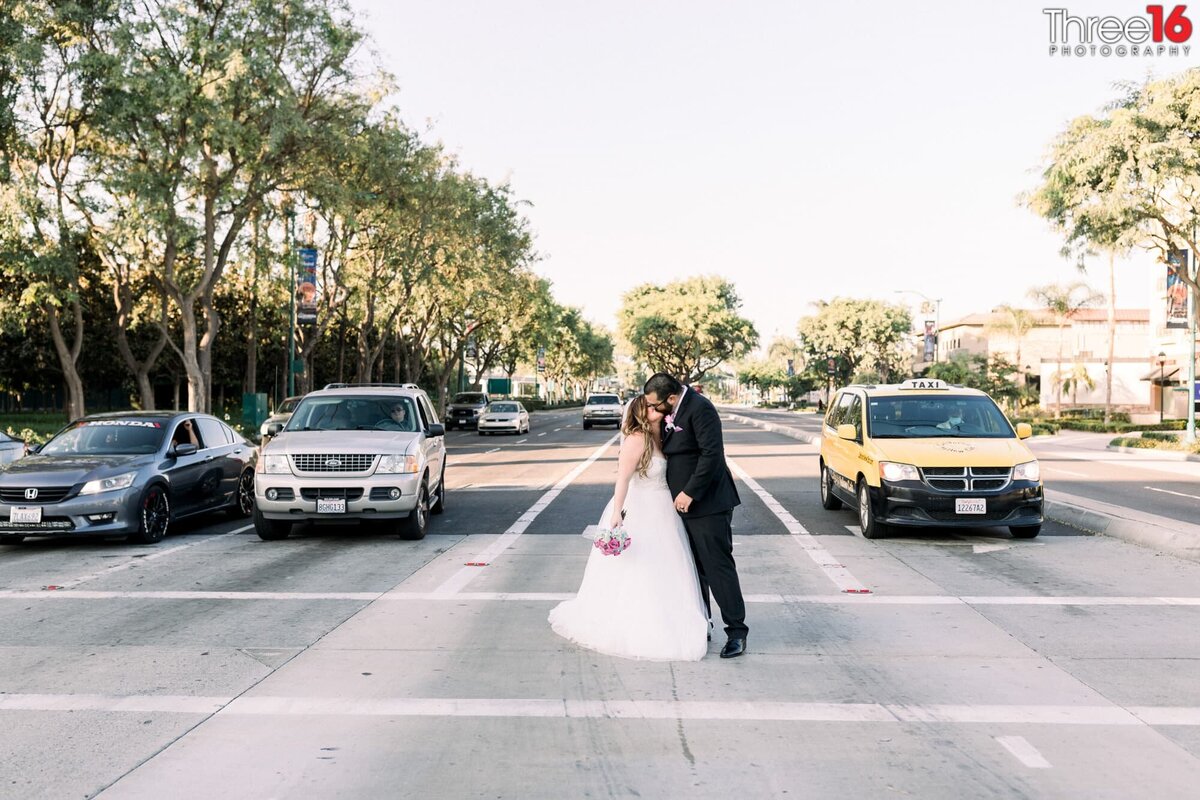 Bride and Groom stop in the crosswalk to share a kiss as stopped cars look on