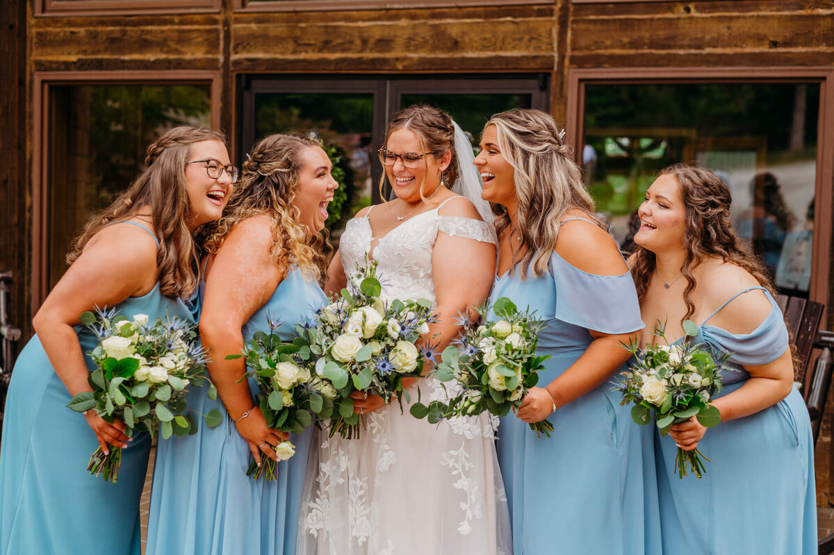Photo of bridesmaids and light blue laughing with their friend, the bride