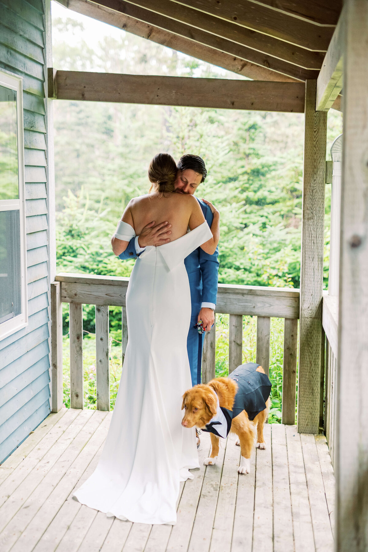 Bride hugging groom on veranda with dog at Oceanstone Resort Wedding in Nova Scotia