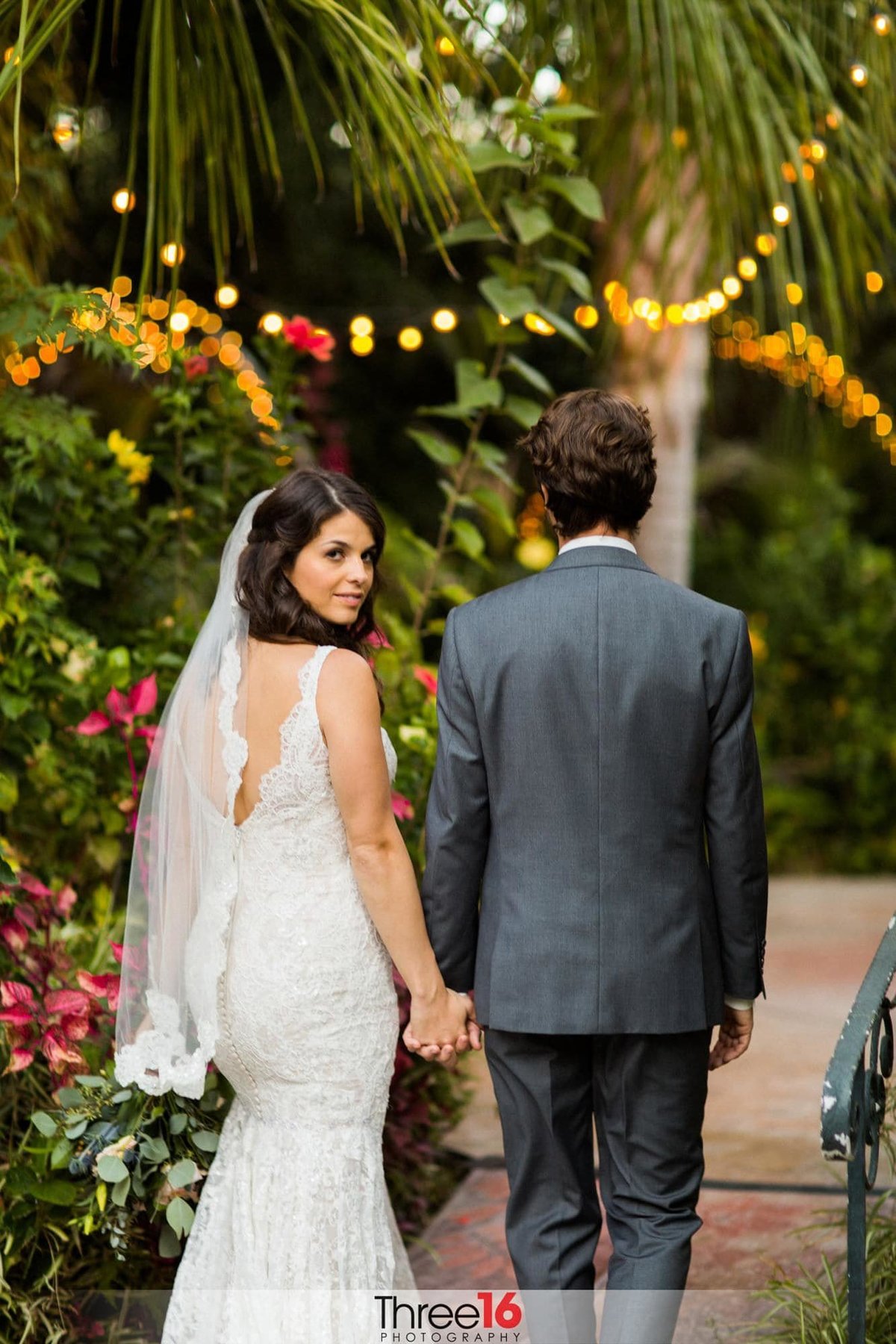 Bride looks back at the camera as the newly married couple walks away holding hands