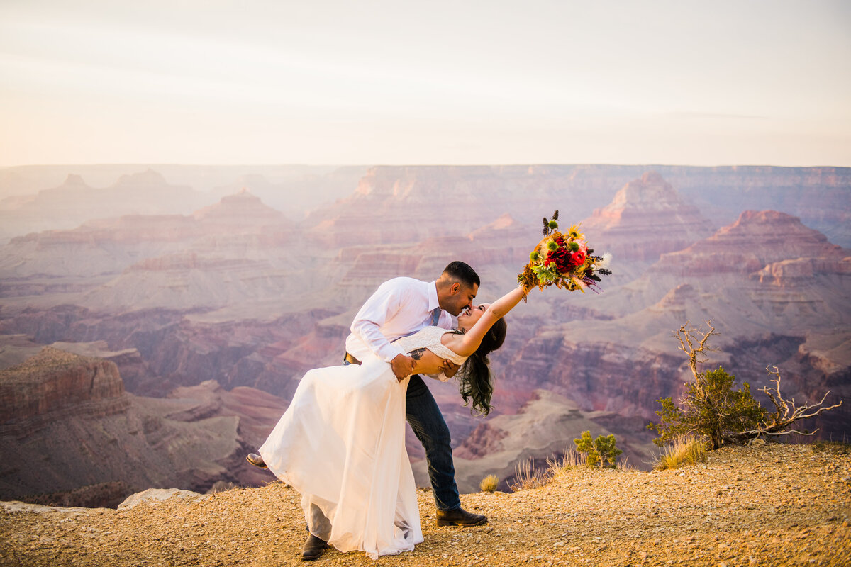 Bride and Groom kissing at Grand Canyon  holding up bouquet sunset