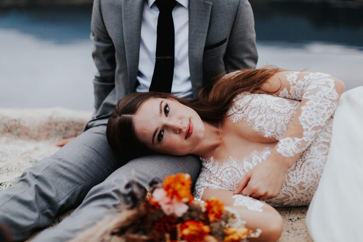bride and groom laying in the sand