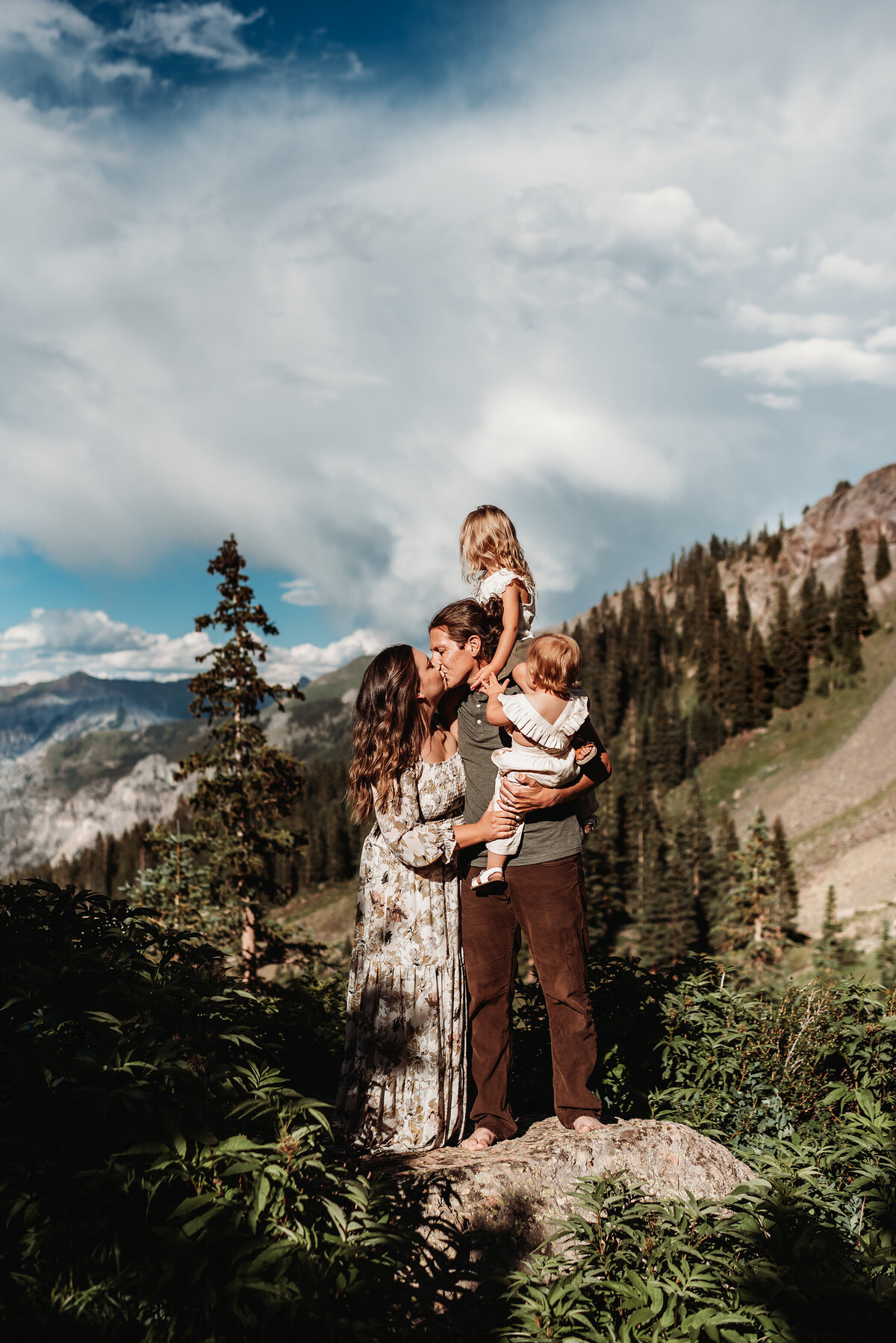 family in Ouray kissing at the top of the mountain in direct sunlight
