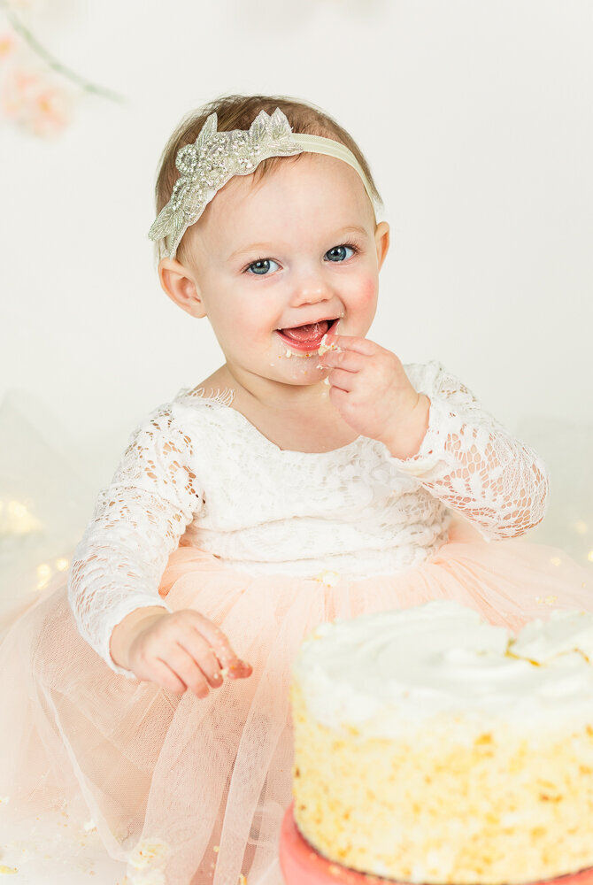 One year old girl eating her cake during cake smash session