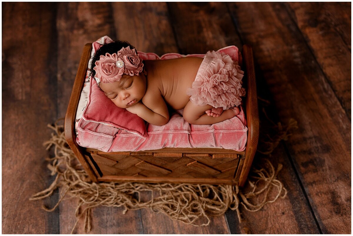 baby girl laying on newborn bed prop